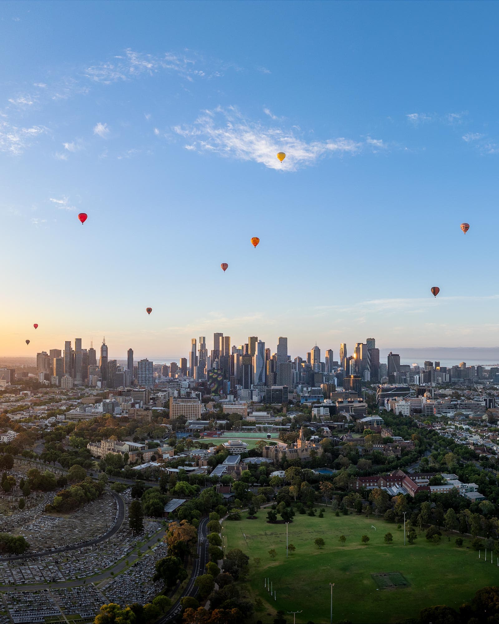 Hot air balloons drifting over Melbourne CBD at sunrise